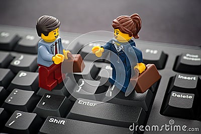 Lego businessman and businesswoman minifigures standing on a black computer keyboard Editorial Stock Photo