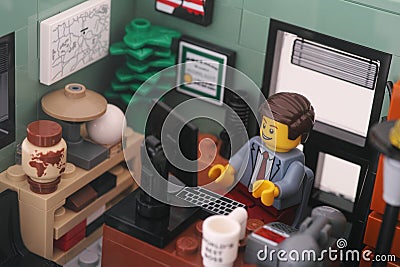 A Lego businessman minifigure sitting and working behind a computer in an office Editorial Stock Photo