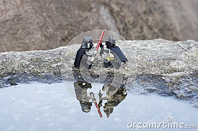 lego darth vader fighting batman with reflection on the pond. Editorial Stock Photo