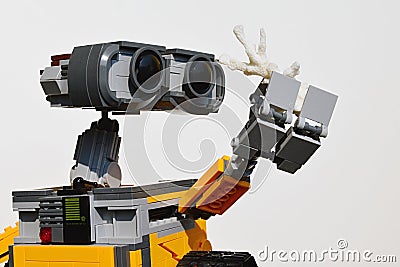 LEGO figure of Wall-E robot from Disney Pixar movie adoring white sea coral in his left arm, light grey background. Editorial Stock Photo