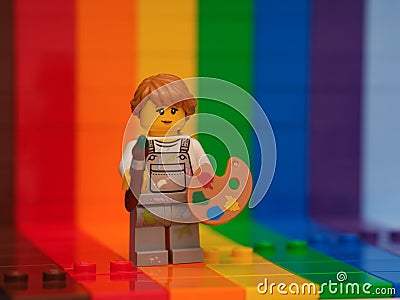 Lego girl painter minifigure with a paintbrush and a palette standing against a rainbow backdrop Editorial Stock Photo