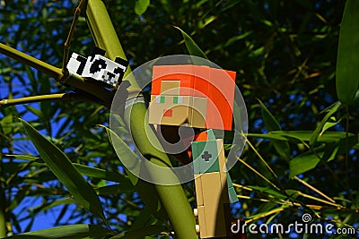 LEGO Minecraft action figure of Alex climbing towards small Panda LEGO Minecraft figure sitting on side branch of real bamboo Editorial Stock Photo