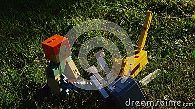 LEGO Minecraft fight scene on garden lawn - Alex with diamond sword and her animal fried Ocelot defeat Skeleton monster mob Editorial Stock Photo