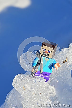 LEGO Minecraft figure of Steve trying to climb on real glacier mountain in winter landscape Editorial Stock Photo