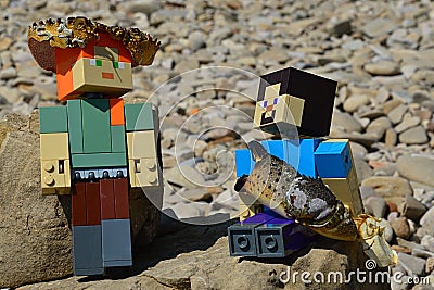 LEGO Minecraft large figures of Steve and Alex on shoreline rock, Alex standing with crab cephalothorax on her head Editorial Stock Photo