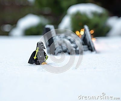 Lego star wars minifigure darth vader walking on the snow with crashed ship tie advanced in the background Editorial Stock Photo