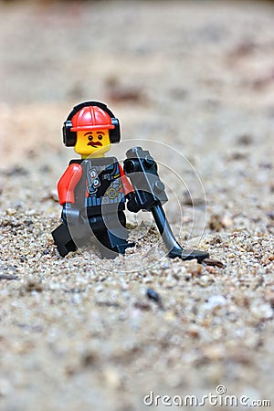 Lego Toy male figure character with a moustache, walking in the sand with a metal detector Editorial Stock Photo