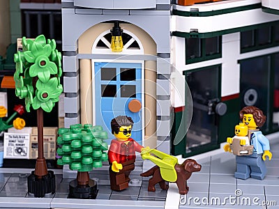 A Lego visually impaired man minifigure with a guide dog walking on a city street with a Lego mother with a baby walking towards Editorial Stock Photo