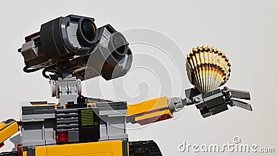 LEGO Wall-E robot holding bivalve seashell of Cockle family, in his left arm, light grey background. Editorial Stock Photo