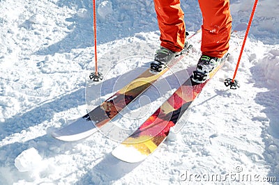 Legs athlete skier in an orange overall on a sport skiing on snow on a sunny day. The concept of winter sports Stock Photo