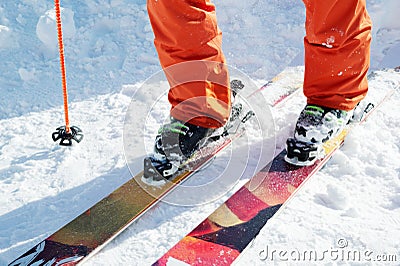 Legs athlete skier in an orange overall on a sport skiing on snow on a sunny day. The concept of winter sports Stock Photo