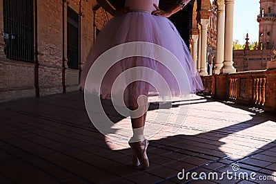 Legs of a classical ballet dancer in which she is standing on tiptoe with her hands on her hips. Classical ballet Stock Photo