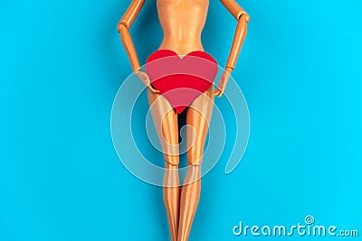 legs of a doll with a red heart covering the crotch on a vibrant blue background Stock Photo