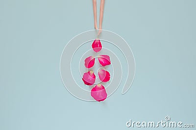 The legs of doll with rose petals drop from them on blue background. Stock Photo