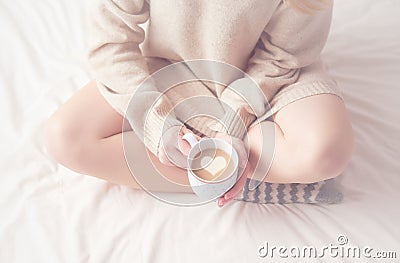 Legs of girl warm woolen socks and cup of coffee warming, winter morning in bed Stock Photo