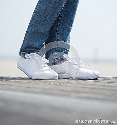 Legs in jeans and comfortable white shoes Stock Photo