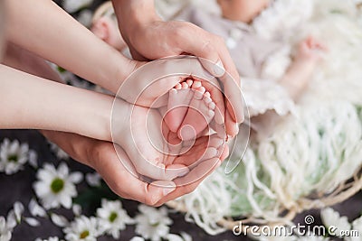 Legs of a newborn baby, a child in the hands of parents, parental love and care Stock Photo