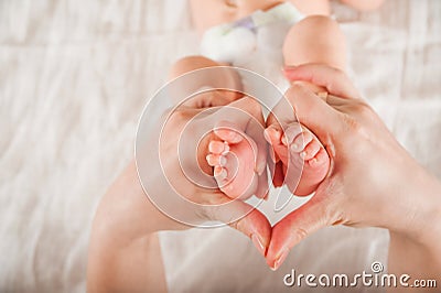 Legs of a newborn in hands closeup. Baby`s feet and copy space. Infant care and colic. Stock Photo