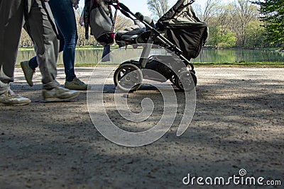 legs of people and a stroller buggie in the park, lake as background Stock Photo