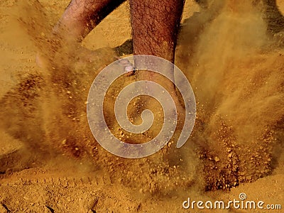 Legs of a person while walking on field ground with thick layer of dirt dust raised Stock Photo