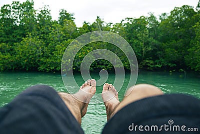 Legs point of view of alone male who sit and sleep over the water surround mangrove forest Stock Photo