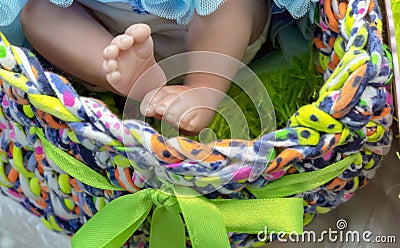 Legs of a realistic baby doll in a multi-colored basket Stock Photo