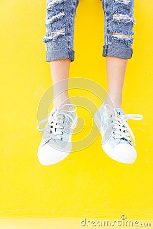 Legs sneakers on yellow background, lifestyle fashion Stock Photo