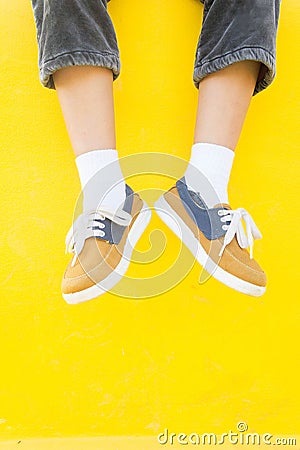 Legs sneakers on yellow background, lifestyle fashion Stock Photo