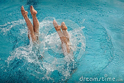 Legs of synchronized swimmers girls peeking out of the pool water in a show performance Stock Photo