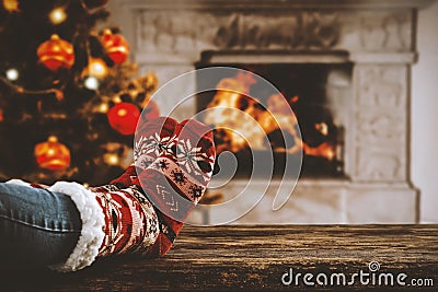 Wooden table with legs in christmas socks with fireplace background and space for your decoration, products and text. Stock Photo