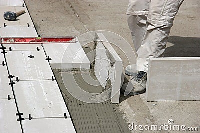 Legs of worker laying tiles Stock Photo