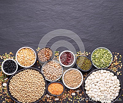 Legumes, lentils, chickpeas and beans assortment in various bowls on black stone background, top view with copy space Stock Photo