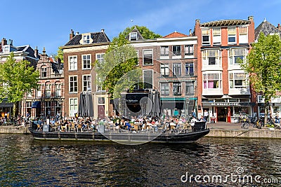 Boat terrace full of people enjoying the sun, food and drinks in the canal of the old town center of Leiden. Blue sky Editorial Stock Photo