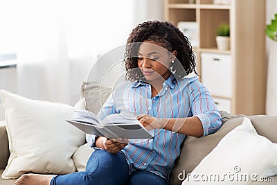 African american woman reading book at home Stock Photo