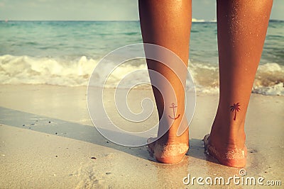 Leisure in summer - Rear of beautiful women tan relax on beach with tattoo on foot Stock Photo