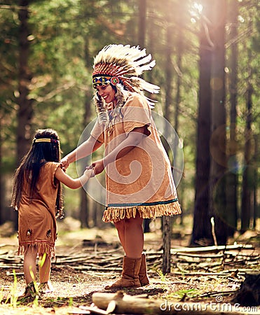 Lemme see your rain dance. a little girl and her mother dancing while playing dressup in the woods. Stock Photo