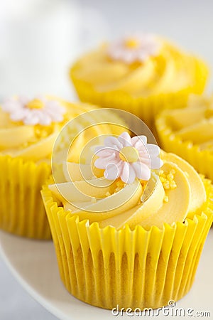 Lemon cupcakes with butter cream swirl and fondant flower decoration Stock Photo