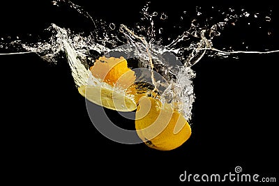 Lemon halves falling deeply under water on black background Stock Photo