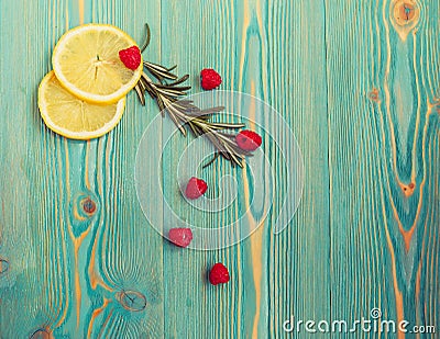 Lemon slices, raspberry and rosemary on turquoise wooden desk Stock Photo