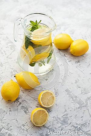 Lemonade close-up on a concrete background with lemons cut open. Whole lemons, mint, fresh summer lemonade in nature, the concept Stock Photo