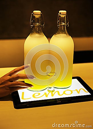 Lemoncello cocktail in two big bottles on table lighted by tablet underneath in cafe Stock Photo