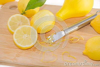 Lemons, squeezer, zest and Zester on wooden cutting board. Stock Photo