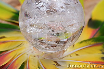 Lemurian Clear Quartz Sphere crystal magical orb in the middle of a circle made of colorful feathers. Stock Photo