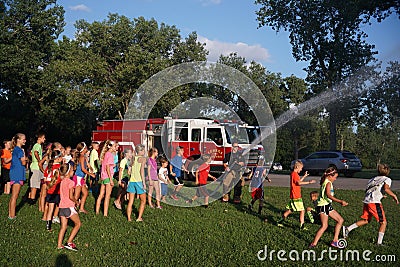 Fire department spraying hose for kids to cool down in summer Editorial Stock Photo