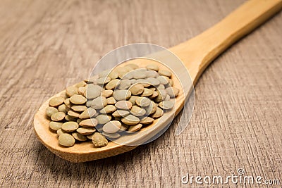 Lentil legume. Spoon and grains over wooden table. Stock Photo