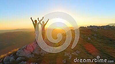 LENS FLARE: Caucasian couple celebrates reaching top of mountain at sunset. Stock Photo