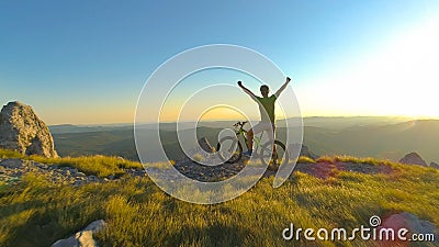 LENS FLARE: Excited athletic man celebrates reaching top of the hill on bike. Stock Photo