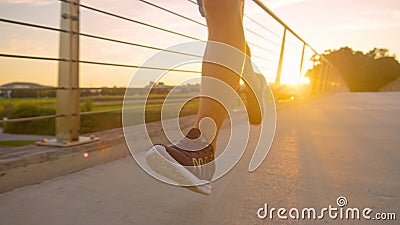 LOW ANGLE: Athletic young man runs across an asphalt bridge on a sunny evening. Stock Photo