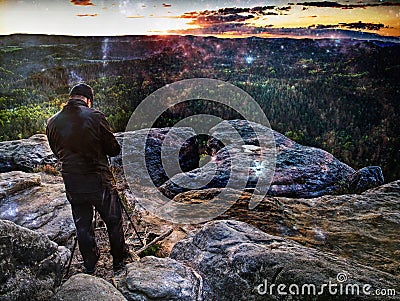 Lens flare. Tourist guide on peak takes photo. Strong hiker with backpack Stock Photo