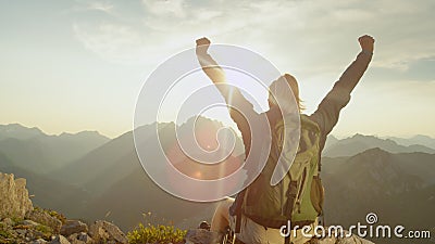 LENS FLARE: Trekker celebrates reaching mountaintop on a sunny summer day. Stock Photo
